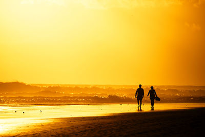 Tourists visiting beach against clear sky