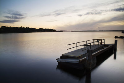 Pier on lake against sky during sunset