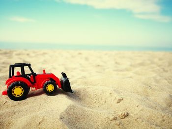 Toy car on sand at beach against sky