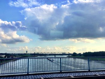 Bridge over river against cloudy sky