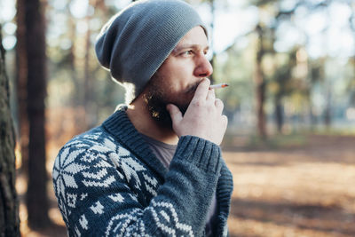 Midsection of man smoking cigarette in forest