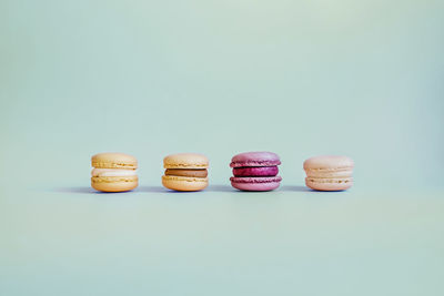 Colored macaroons led by a bright purple on a turquoise background in the center of the picture.