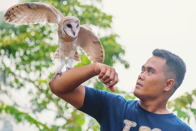 Man holding barn owl at park