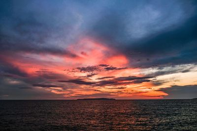 Scenic view of sea against dramatic sky during sunset
