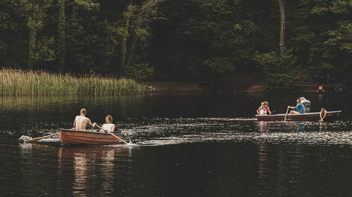 People sitting on boat in lake against trees