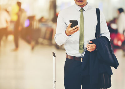 Midsection of man holding mobile phone