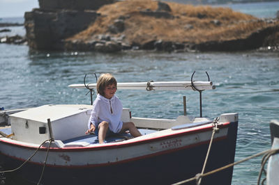 Rear view of boy on boat in sea