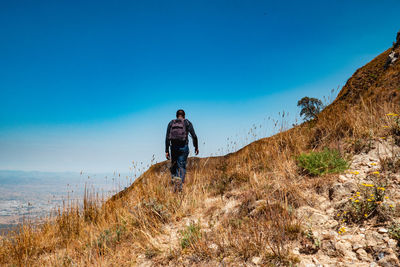 Rear view of a hiker against a valley at mbeya peak in mbeya, tanzania 