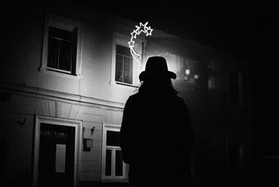 Silhouette woman standing against building at night