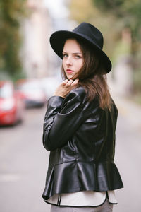 Portrait of young woman outside wearing black hat and leather jacket