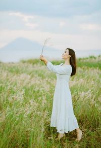 Young woman with arms raised standing on field