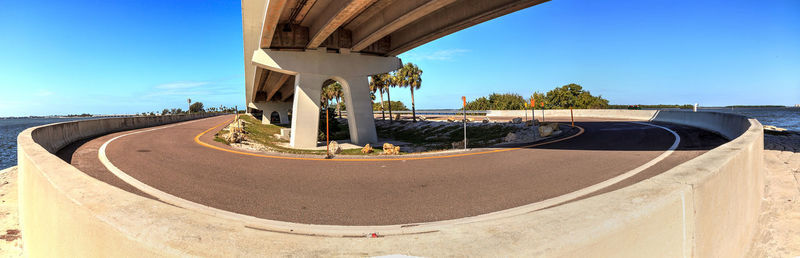 Road by built structure against blue sky