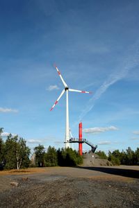 Wind turbine and viewing platform on field against sky