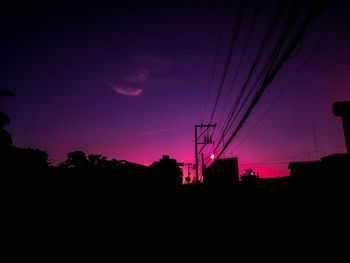 Low angle view of silhouette electricity pylon against sky during sunset