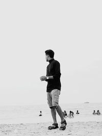 Full length of man standing on beach against clear sky