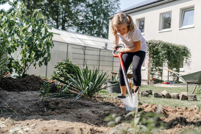 Smiling girl with shovel gardening in backyard