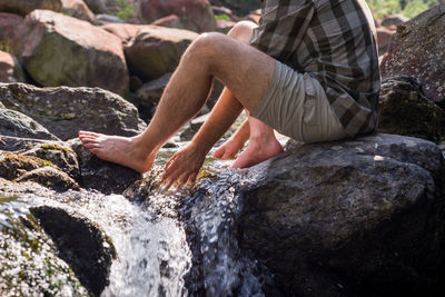 Low section of man sitting on rock