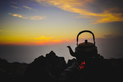 Silhouette rock on mountain against sky during sunset