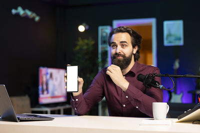 Portrait of young man using mobile phone in office