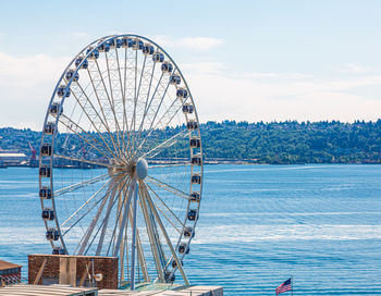 Ferris wheel by sea against sky