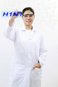 Portrait of doctor writing h1n1 while standing against white background