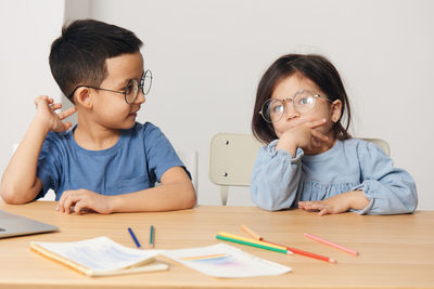 Smiling kids sitting by table