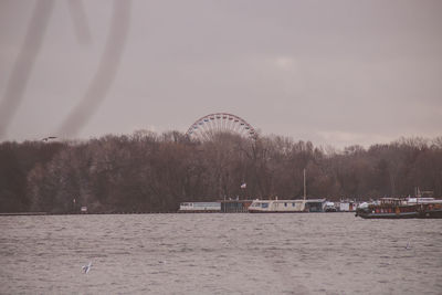 Ferris wheel by river against sky