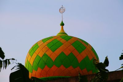 Low angle view of multi colored temple against building against clear sky