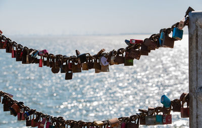 Close-up of love locks hanging on chain against sea