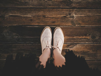 Low section of woman standing on wooden floor