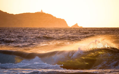 Sea waves splashing on shore against sky