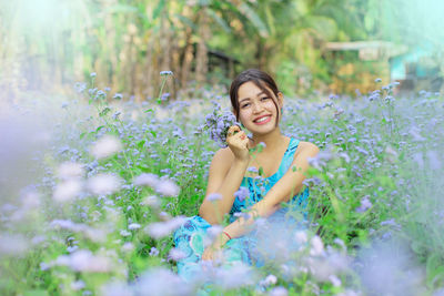 Portrait of smiling woman sitting amidst flowers