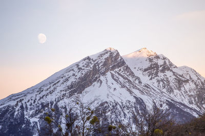 Low angle view of snowcapped mountain against clear sky during sunset