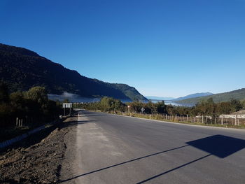 Road by mountains against clear blue sky