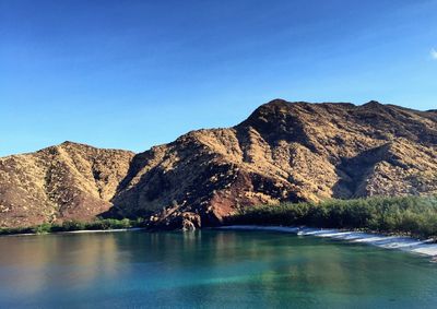 Scenic view of sea and mountains against clear blue sky