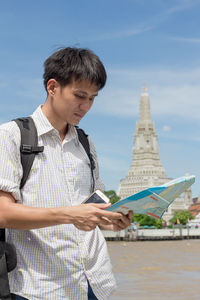 Young man standing at historic building against sky