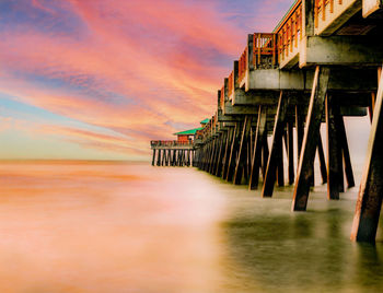 Pier over sea against sky during sunset