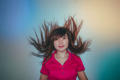 Portrait of beautiful young woman standing against wall