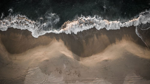 Aerial view of sea waves rushing at beach