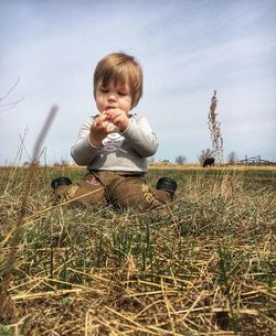 Cute boy on field against sky