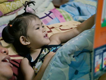 A baby girl, 2 years old, enjoys reading a story or book together with her mother