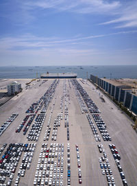 Aerial logistics commercial vehicles waiting to be load on to a car carrier ship at dockyard