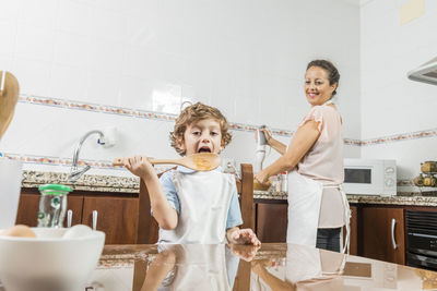 Mother looking at son licking son in kitchen