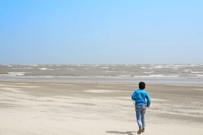 Rear view of man looking at sea against clear sky