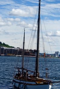 Boats in harbor against cloudy sky