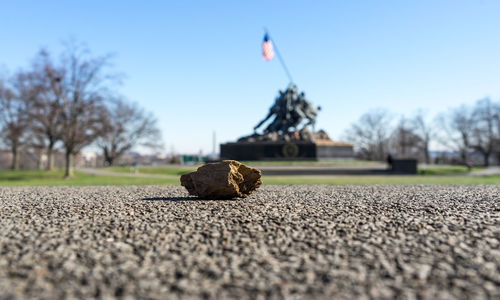 Surface level of statues holding american flag against sky