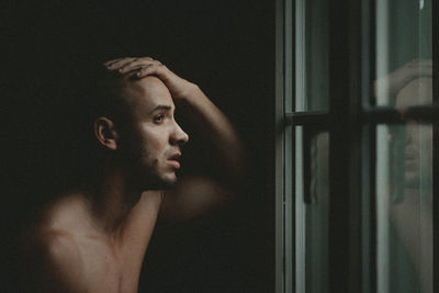 Close-up of depressed man looking through window at home