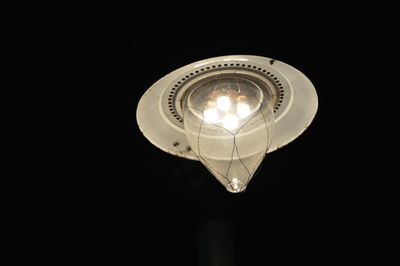 Low angle view of illuminated light bulb against black background
