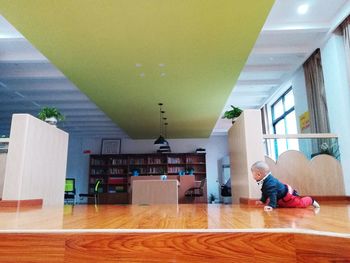 Rear view of boy sitting on hardwood floor at home