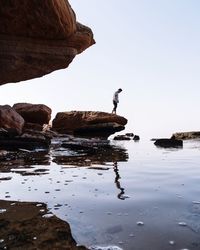 Scenic view of rock formation in sea against clear sky